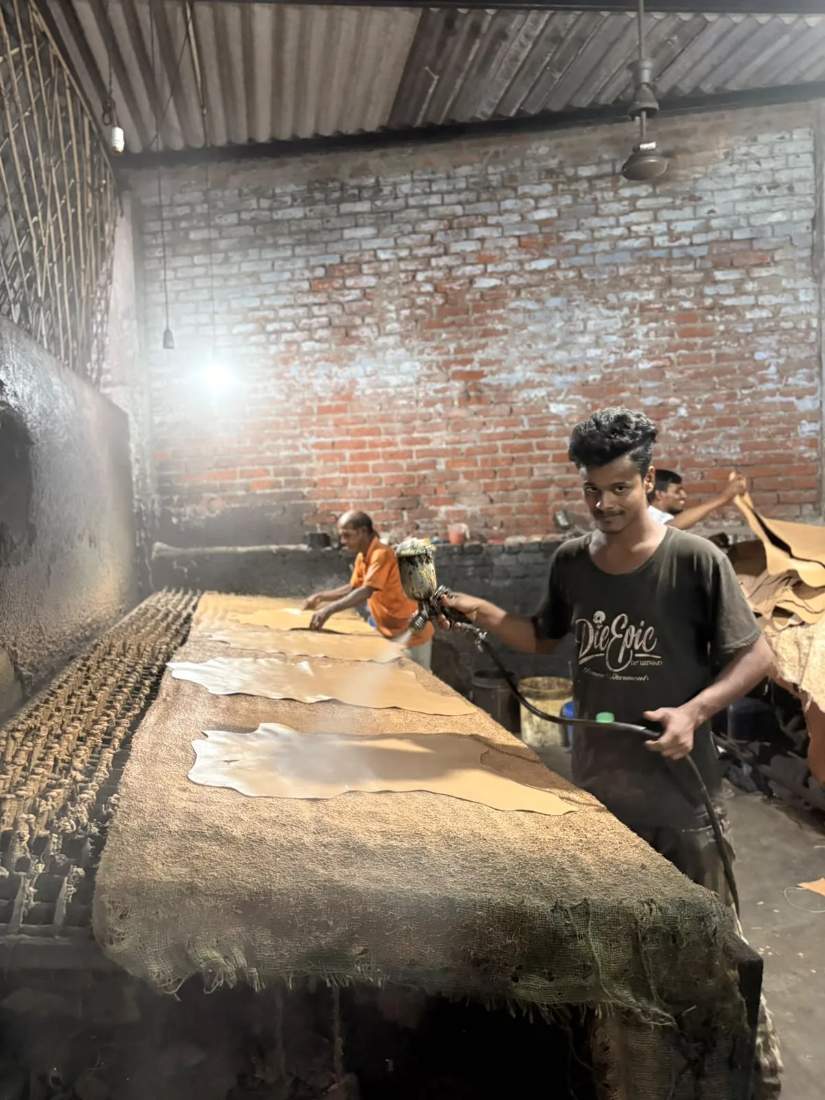 A worker hand-spraying finish onto leather hides in the Alam’s International factory in Kanpur